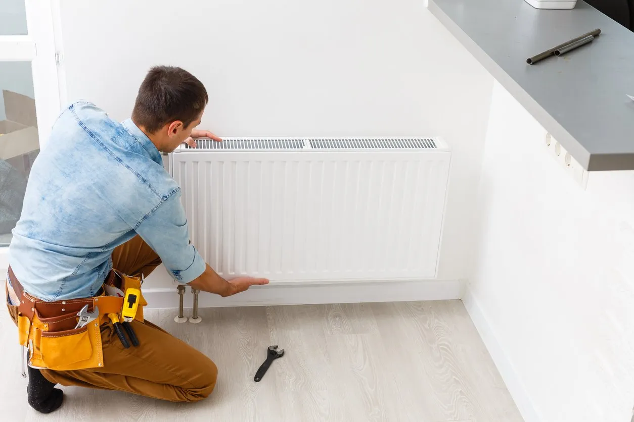 Manisrepairingradiatorbatteryintheroom.Maintenancerepairworksrenovationintheflat.Heatingrestoration.Wrenchinhands.stockphoto 1920w