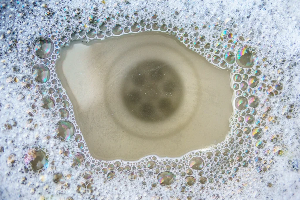 A close-up view of a sink drain with a ring of soapy suds around the edge in Des Moines, IA