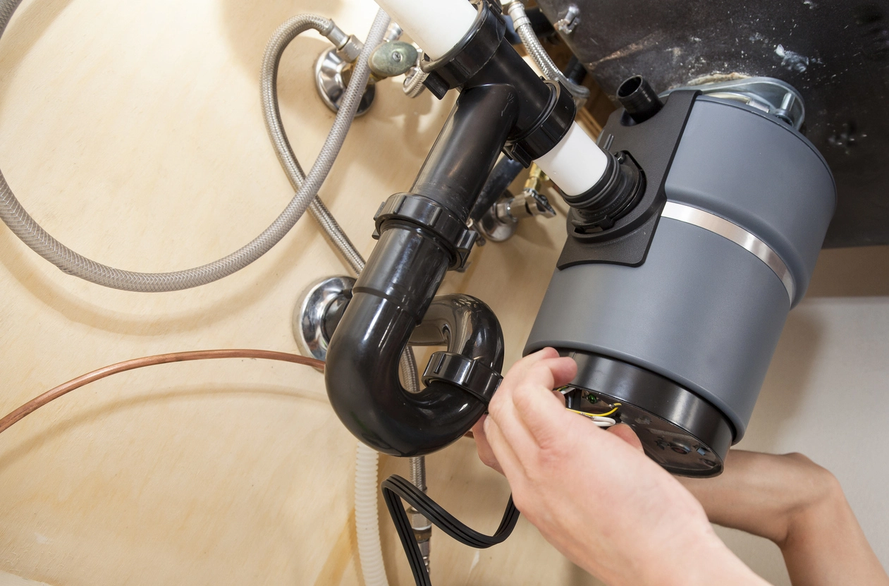 A technician performing garbage disposal repair services in Des Moines, IA